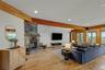 Stone-clad fireplace with hearth, wood-finish flooring, exposed wood beams, recessed lighting, and multiple windows