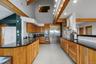 Kitchen featuring natural wood cabinetry, dark countertops, a stainless steel refrigerator, double ovens, and a tile backsplash