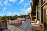 Expansive wood deck with string lighting, multiple seating areas, and a built-in outdoor kitchen