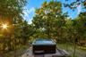 Outdoor hot tub with integrated steps, surrounded by natural landscaping and mature trees
