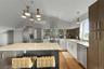 Spacious kitchen featuring an angled ceiling, large center island with stone countertop, stainless steel appliances, and a tiled backsplash