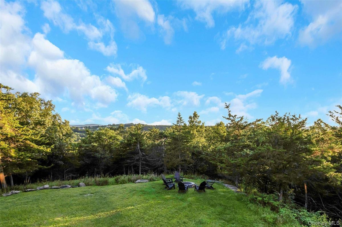Expansive lawn with a built-in fire pit, surrounded by mature trees and natural landscaping