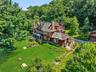 As we start to rise above the home, we can appreciate the craftsmanship of the cedar roof, the beauty of the brick chimneys, and the convenience and s