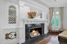 At the head of the dining room is another dramatic fireplace, with original tile. It is surrounded by intricate woodwork on the mantel and pilasters. 