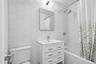 Bathroom featuring hexagon wall tiling, white vanity with integrated sink, full bathtub