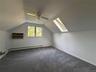 Vaulted ceiling with a ceiling fan, skylight, wall-mounted air conditioning unit, baseboard heating, and gray carpeting