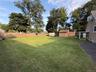 oversized rear yard with mature trees, a wood privacy fence, and two storage sheds