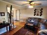 Hardwood flooring, painted walls, crown molding, ceiling fan with integrated lighting, and a staircase with wood railings