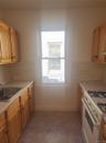 Kitchen featuring light wood-finish cabinetry, tile flooring, a gas range, a stainless steel sink, and a window