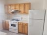 Kitchen featuring light wood cabinetry, white countertops, textured tile backsplash, a gas range, and a full-size refrigerator