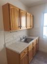 Light wood cabinetry with arch panel doors and dark hardware