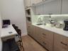 Compact kitchen area featuring wood-finish flooring, light-toned cabinetry with dark hardware, built-in microwave, white solid surface countertops, an
