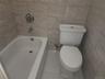 White porcelain bathtub with chrome fixtures and light-toned, rectangular wall tiling