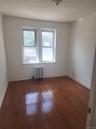 Hardwood flooring with a glossy finish, double windows with white trim, and a wall-mounted radiator