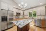 Custom kitchen with center island and snack bar, stainless appliances including double ovens, granite counters and wood floors
