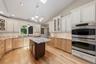 Custom kitchen with center island and snack bar, stainless appliances including double ovens, granite counters and wood floors
