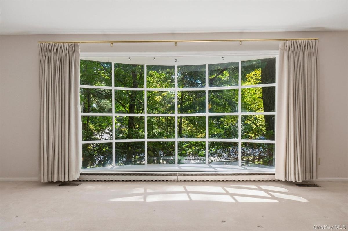 Expansive formal living room with large bow window and wood burning fireplace. Hardwood under carpet.