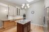 Custom kitchen with center island and snack bar, stainless appliances including double ovens, granite counters and wood floors