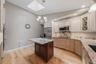 Custom kitchen with center island and snack bar, stainless appliances including double ovens, granite counters and wood floors