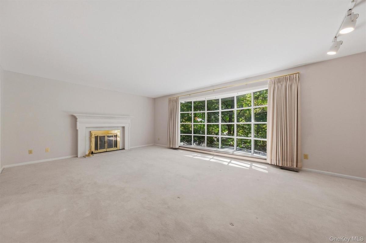 Expansive formal living room with large bow window and wood burning fireplace. Hardwood under carpet.