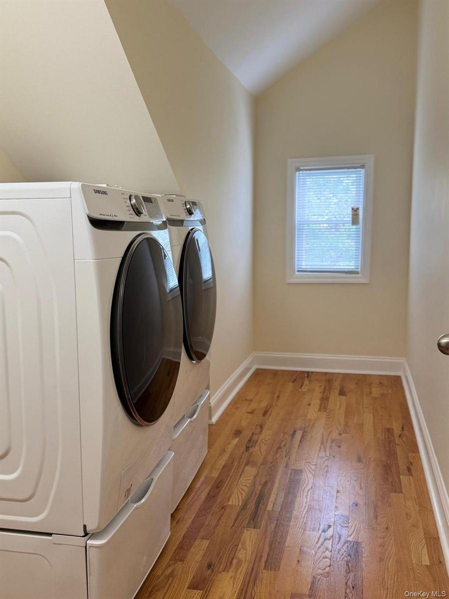 Wood-finish flooring, white trim, and a window with blinds