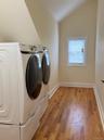 Wood-finish flooring, white trim, and a window with blinds