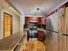 Kitchen featuring wood-finish flooring, stainless steel appliances, granite countertops, wood cabinetry, and a built-in breakfast bar