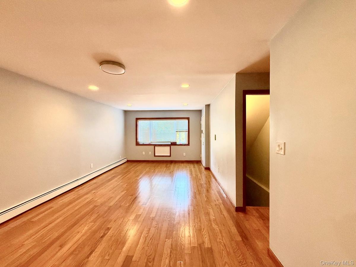 Hardwood flooring, recessed lighting, ceiling-mounted light fixture, window with wood trim, and baseboard heating