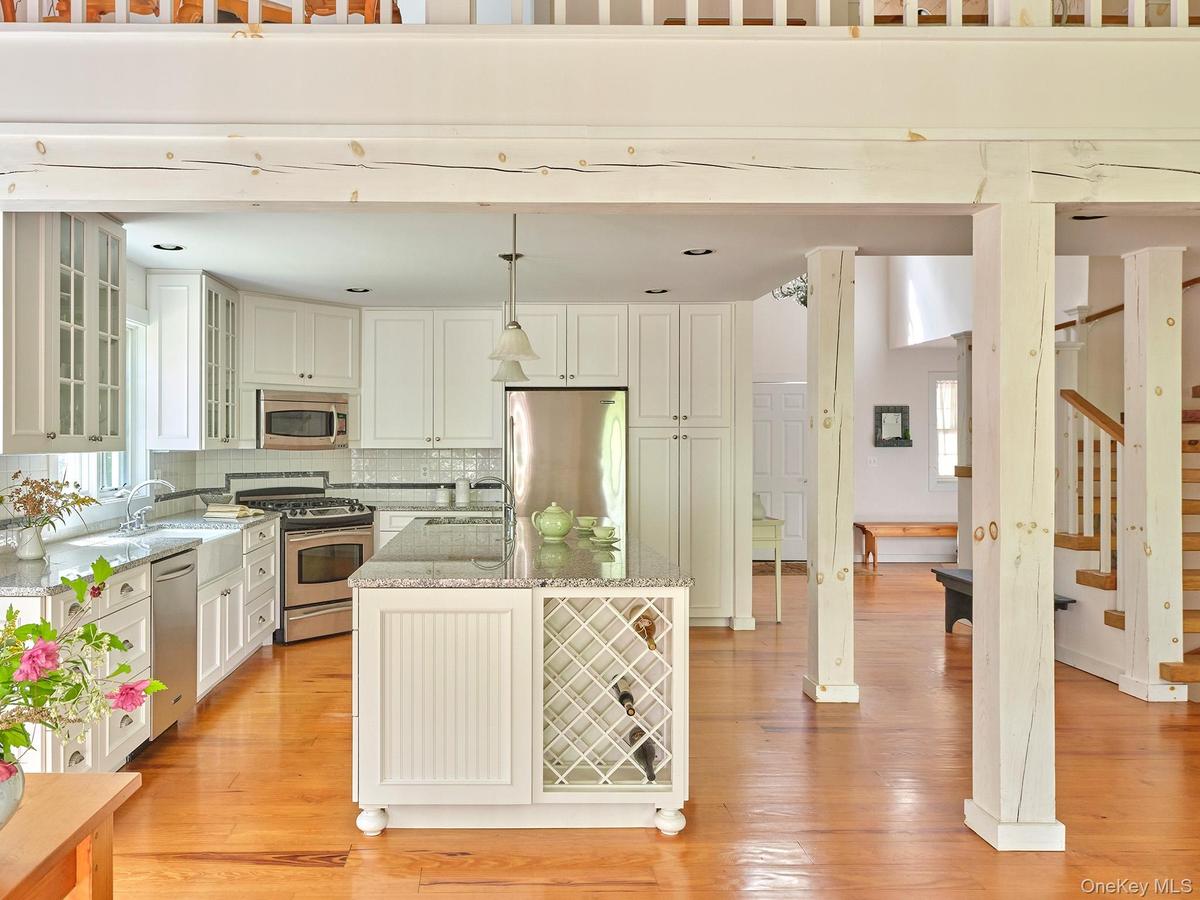 Kitchen featuring glass insert cabinets, light stone countertops, hanging light fixtures, backsplash, and appliances with stainless steel finishes