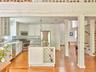 Kitchen featuring glass insert cabinets, light stone countertops, hanging light fixtures, backsplash, and appliances with stainless steel finishes