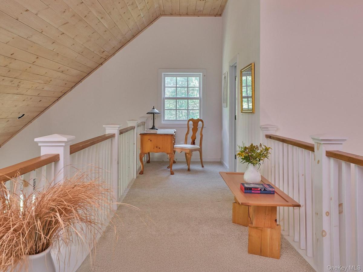 Corridor featuring wooden ceiling, vaulted ceiling, light colored carpet, and an upstairs landing
