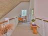 Corridor featuring wooden ceiling, vaulted ceiling, light colored carpet, and an upstairs landing