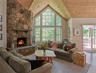 Living room with wainscoting, wood ceiling, a stone fireplace, high vaulted ceiling, and wood finished floors