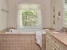 Full bath with vanity, a garden tub, and plenty of natural light