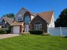 Brick and siding exterior with arched windows, attached garage, and a paver driveway