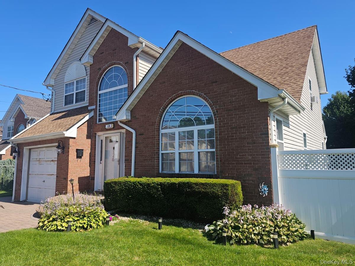 Brick and siding exterior with arched windows, attached garage, and a lattice-top fence