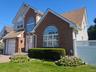 Brick and siding exterior with arched windows, attached garage, and a lattice-top fence