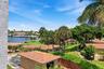 Waterfront property with mature palm trees, manicured lawns, and terracotta-tiled roofs
