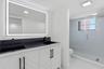 Dual vanity with integrated sinks, black countertop, and white cabinetry