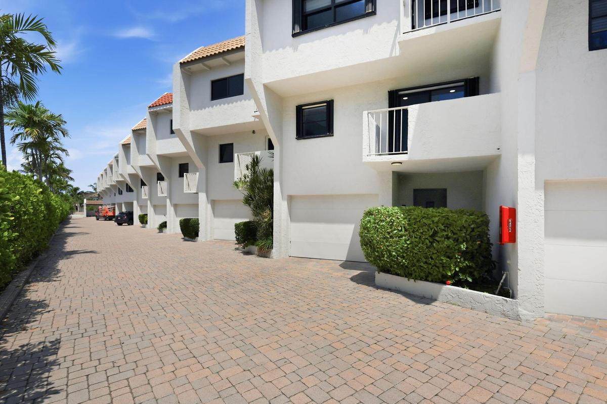 Stucco exterior with white finish, integrated private balconies, attached garages, and a paver driveway