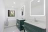 Dual green fluted vanities with integrated sinks, quartz countertops, and lighted mirrors