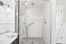 Glass-enclosed shower with subway tile walls, dual showerheads, and mosaic tile flooring