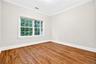 Hardwood flooring, crown molding, white trim, and a window with natural light
