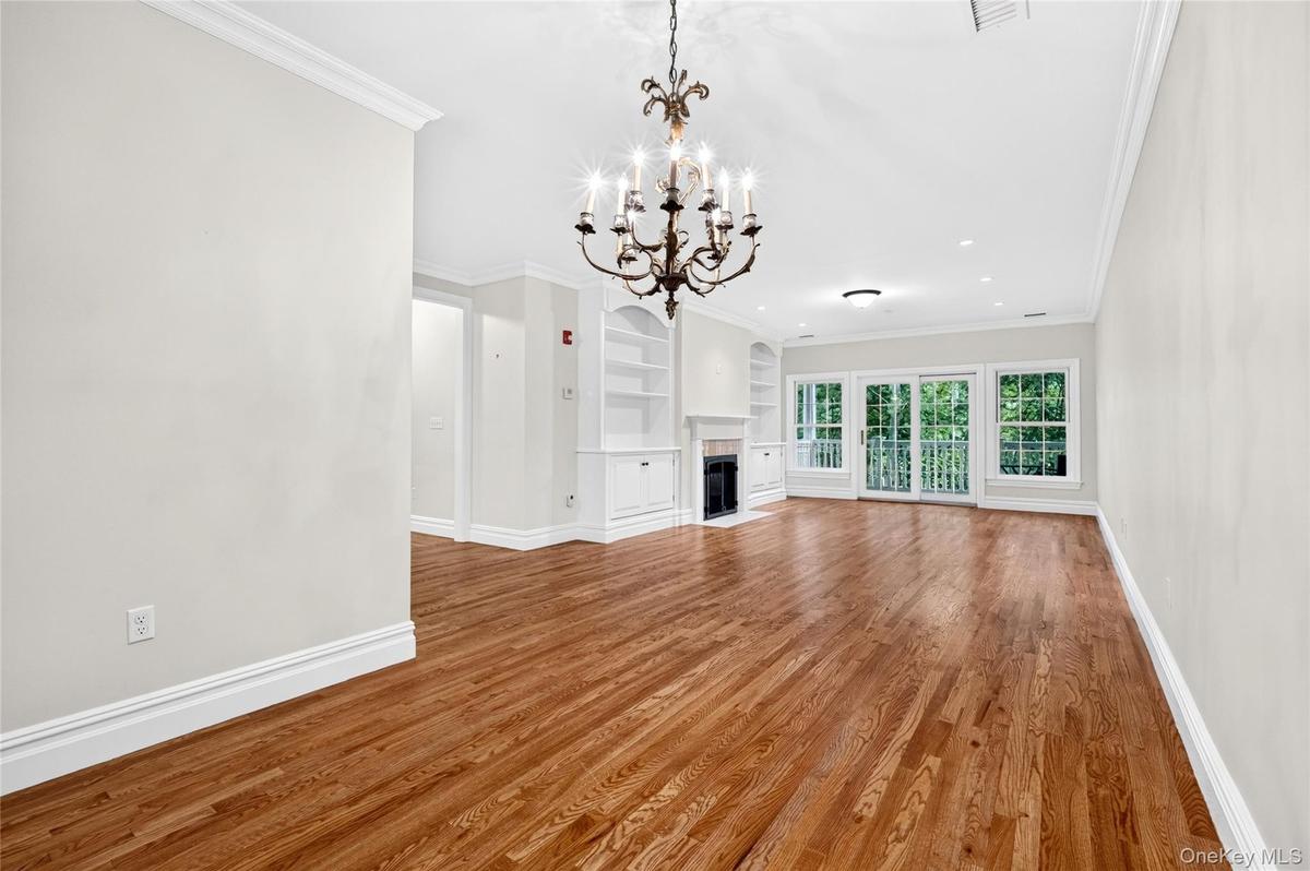 Hardwood flooring, crown molding, built-in shelving, fireplace, and sliding glass doors