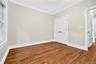 Hardwood flooring, crown molding, white trim, double French doors, and a window with white casing