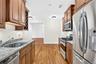Kitchen featuring wood-finish flooring, granite countertops, stainless steel appliances, and wood cabinetry with a built-in wine rack