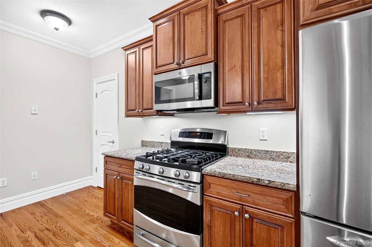 Wood-finish flooring, cherry-toned cabinetry, granite countertops, and stainless steel appliances