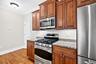 Wood-finish flooring, cherry-toned cabinetry, granite countertops, and stainless steel appliances