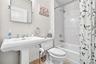 White pedestal sink with chrome fixtures, white subway tile shower surround, and a built-in bathtub