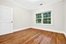 Hardwood flooring, crown molding, white trim, window with grid panes, and a paneled door
